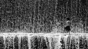 A child walking in the midst of waterfall.